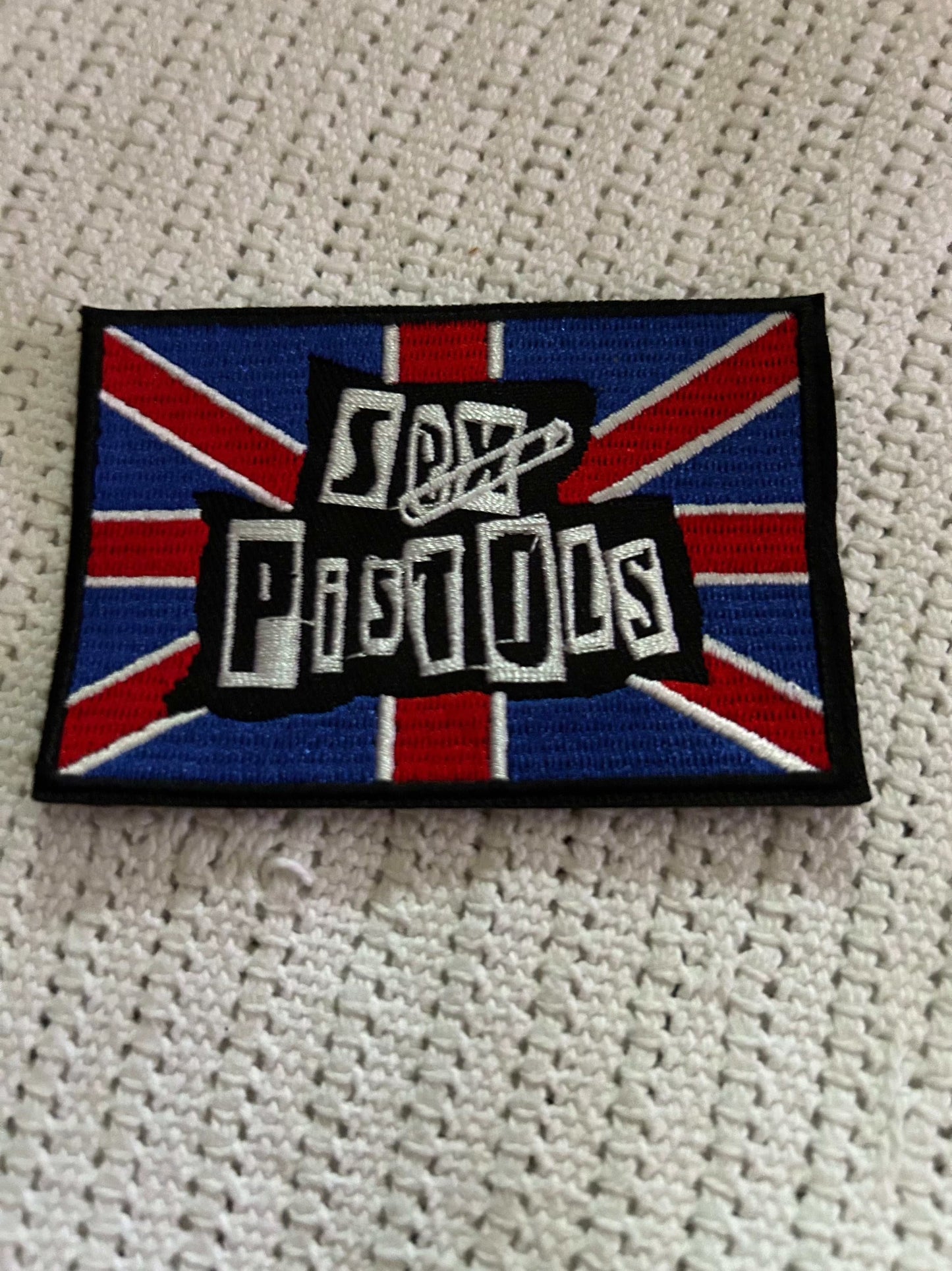 S*x Pistols patch with bold white text on a blue and red Union Jack background, embroidered and iron-on backing
