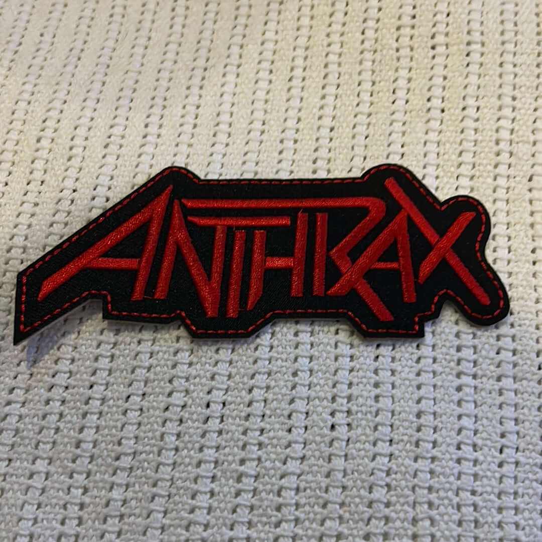 Embroidered Anthrax logo patch in red and black with detailed stitching on textured white fabric background