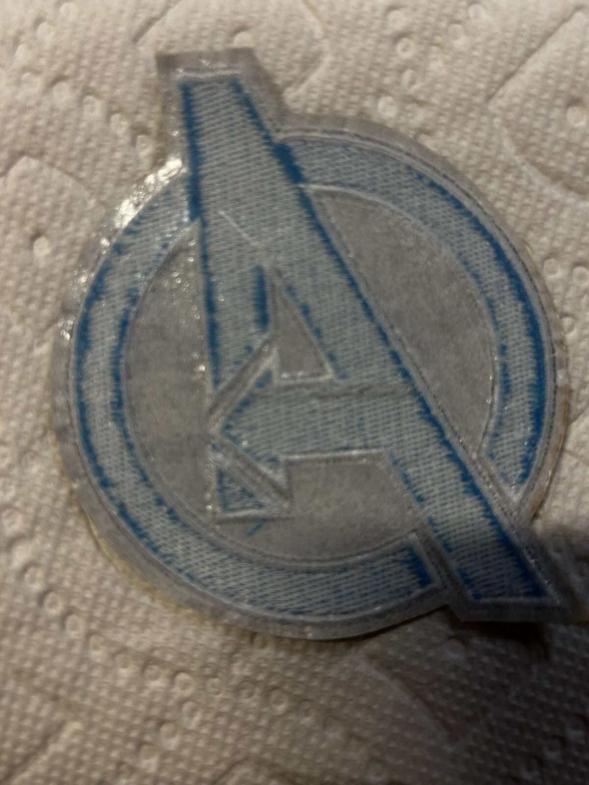 Avengers Assemble embroidered patch blue and black logo on a textured background.
