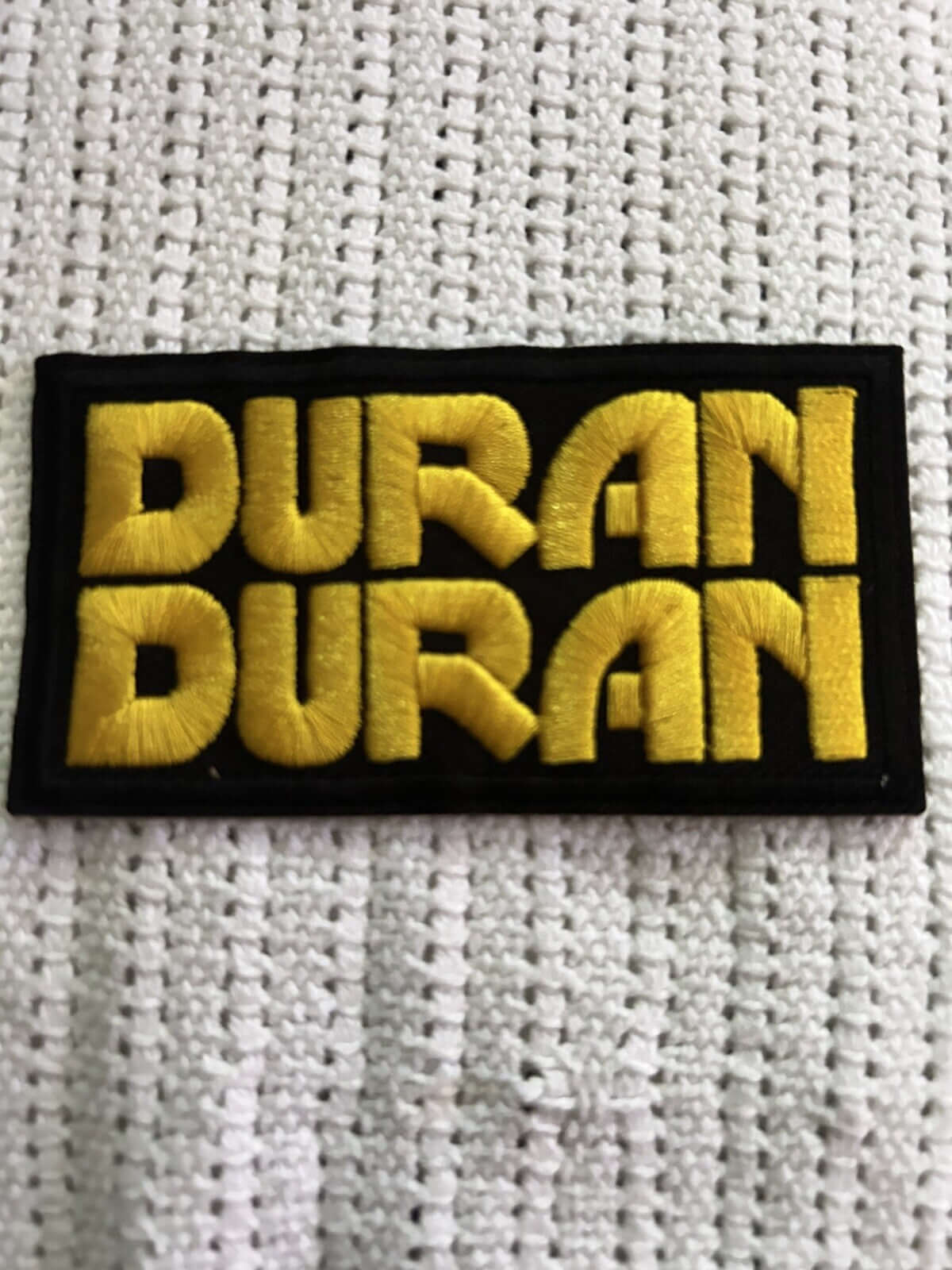 Duran Duran embroidered patch in yellow on a black background, perfect for bags, jackets, or crafts.