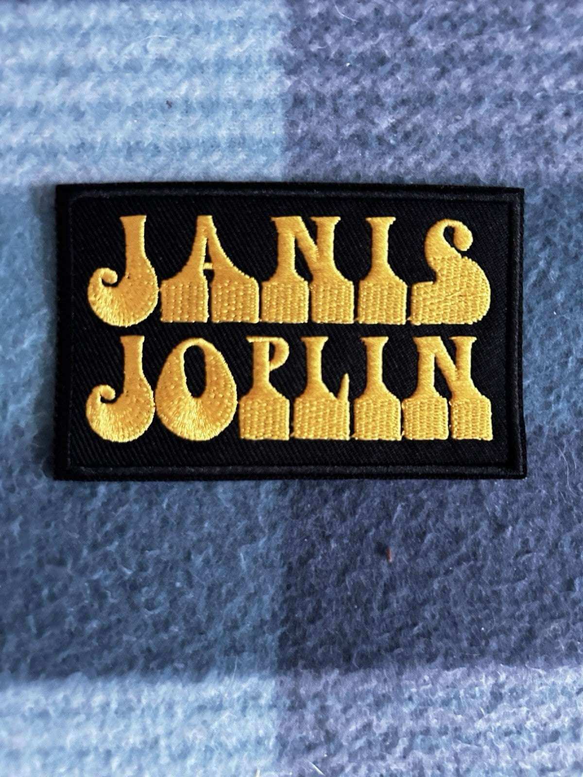 JANIS JOPLIN embroidered patch featuring bold yellow lettering on a black background.
