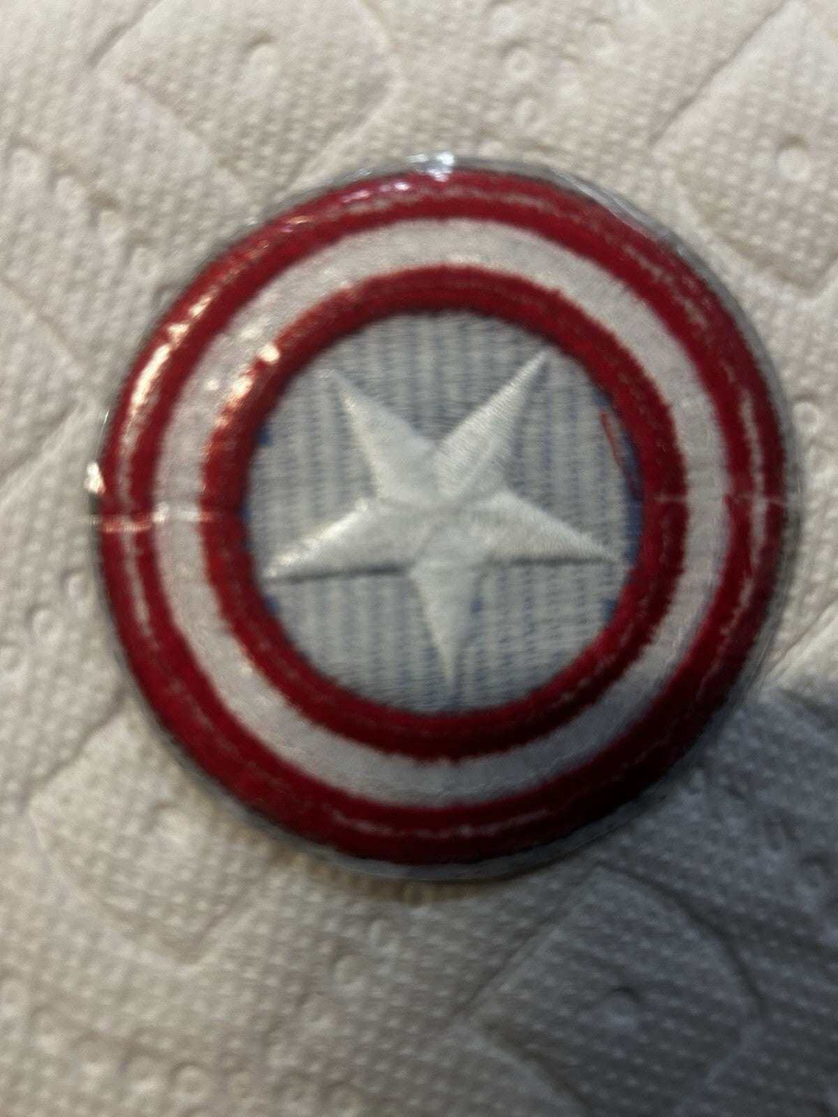 Captain America embroidered iron-on patch on a textured background, measuring 2.75" x 2.75".