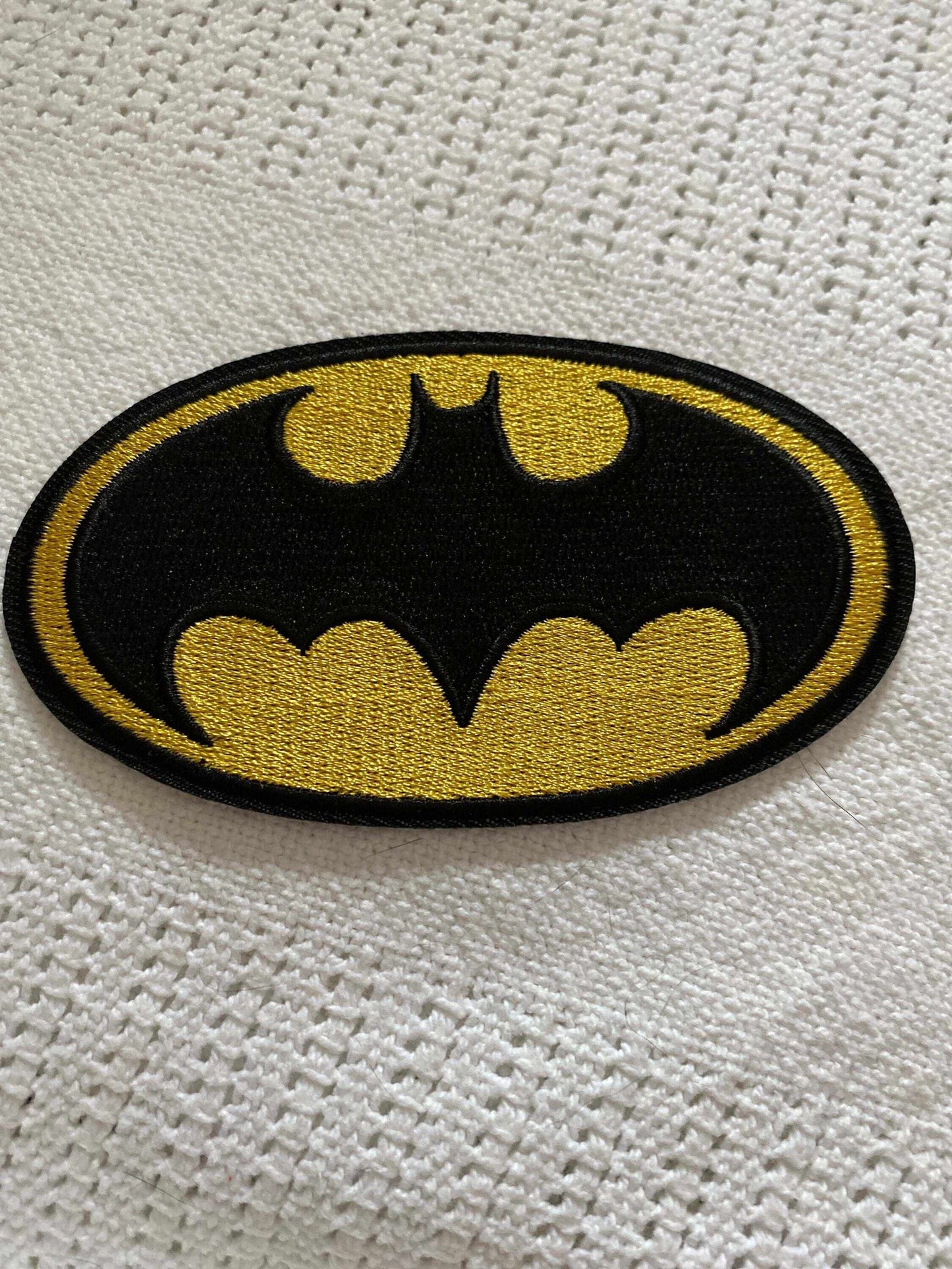 Embroidery of the classic yellow and black Batman 1989 movie logo patch on fabric