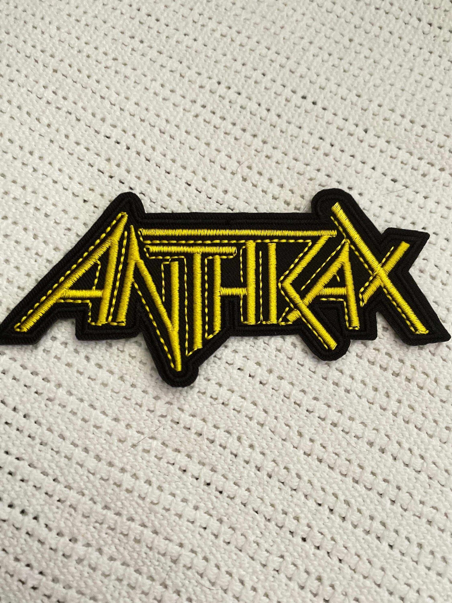 Anthrax logo patch in bold yellow embroidery on black background, perfect for thrash metal fans and bold style.