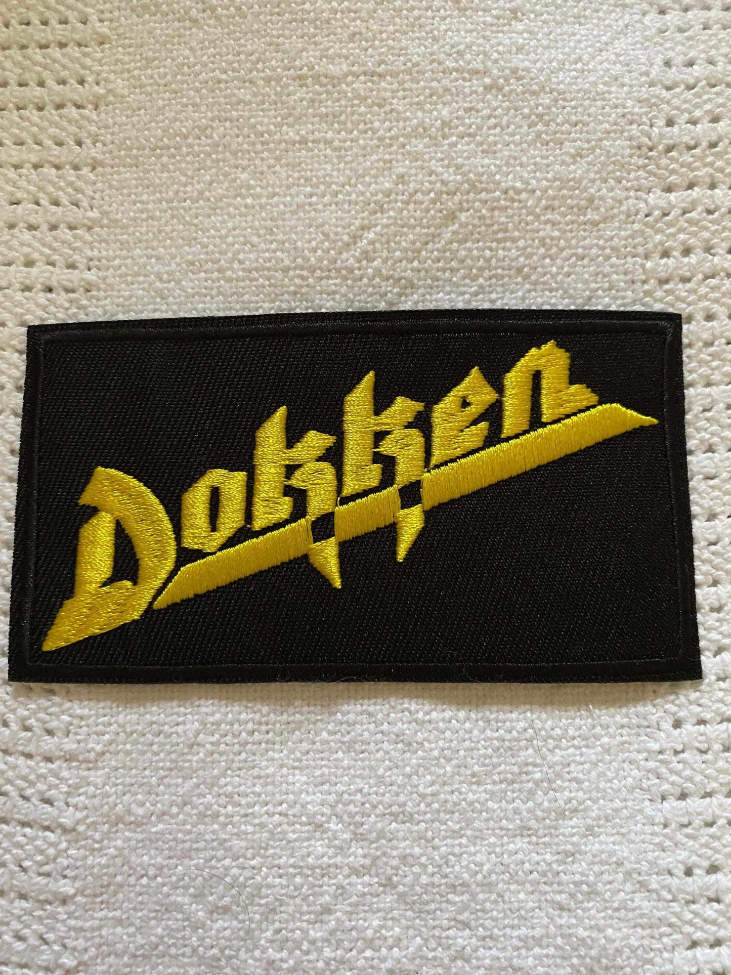 Dokken band logo embroidered patch in yellow on black background