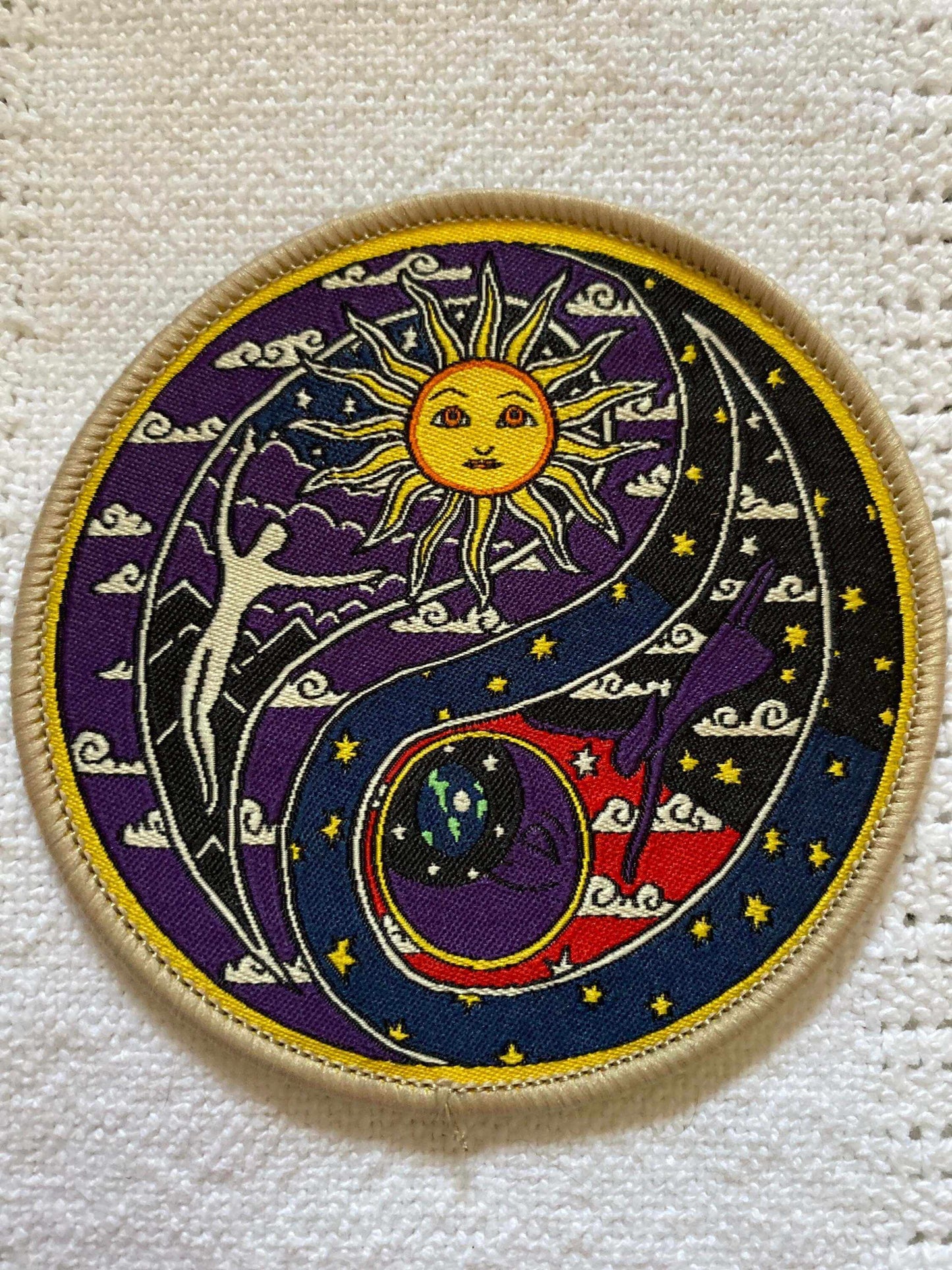 Round embroidered patch featuring Celestial Sun Moon Yin Yan symbol with radiant sun, crescent moon, stars, and human figures in vibrant colors on a purple background