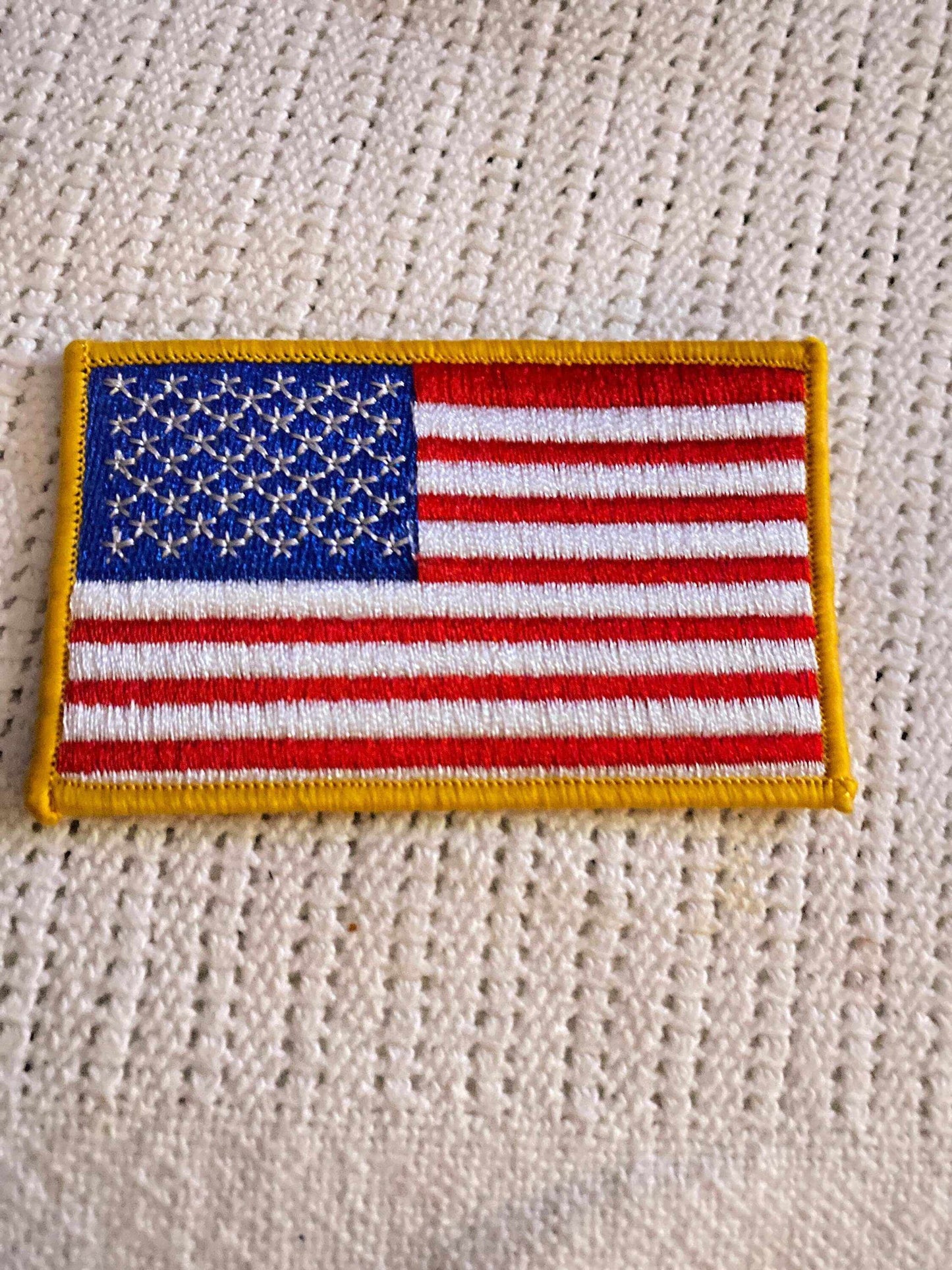 Embroidered American Flag patch with stars and stripes on white textured fabric background
