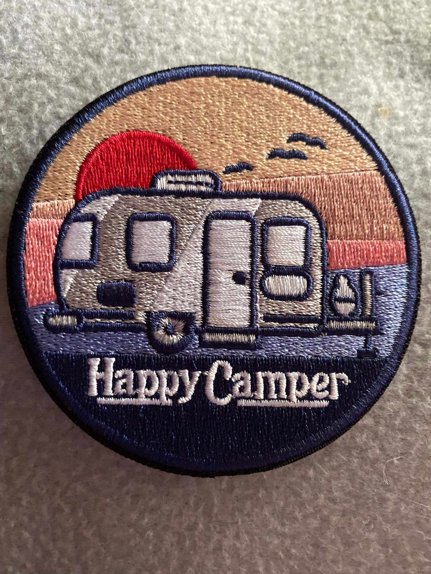 Embroidered patch of a camper trailer at sunset with the text Happy Camper