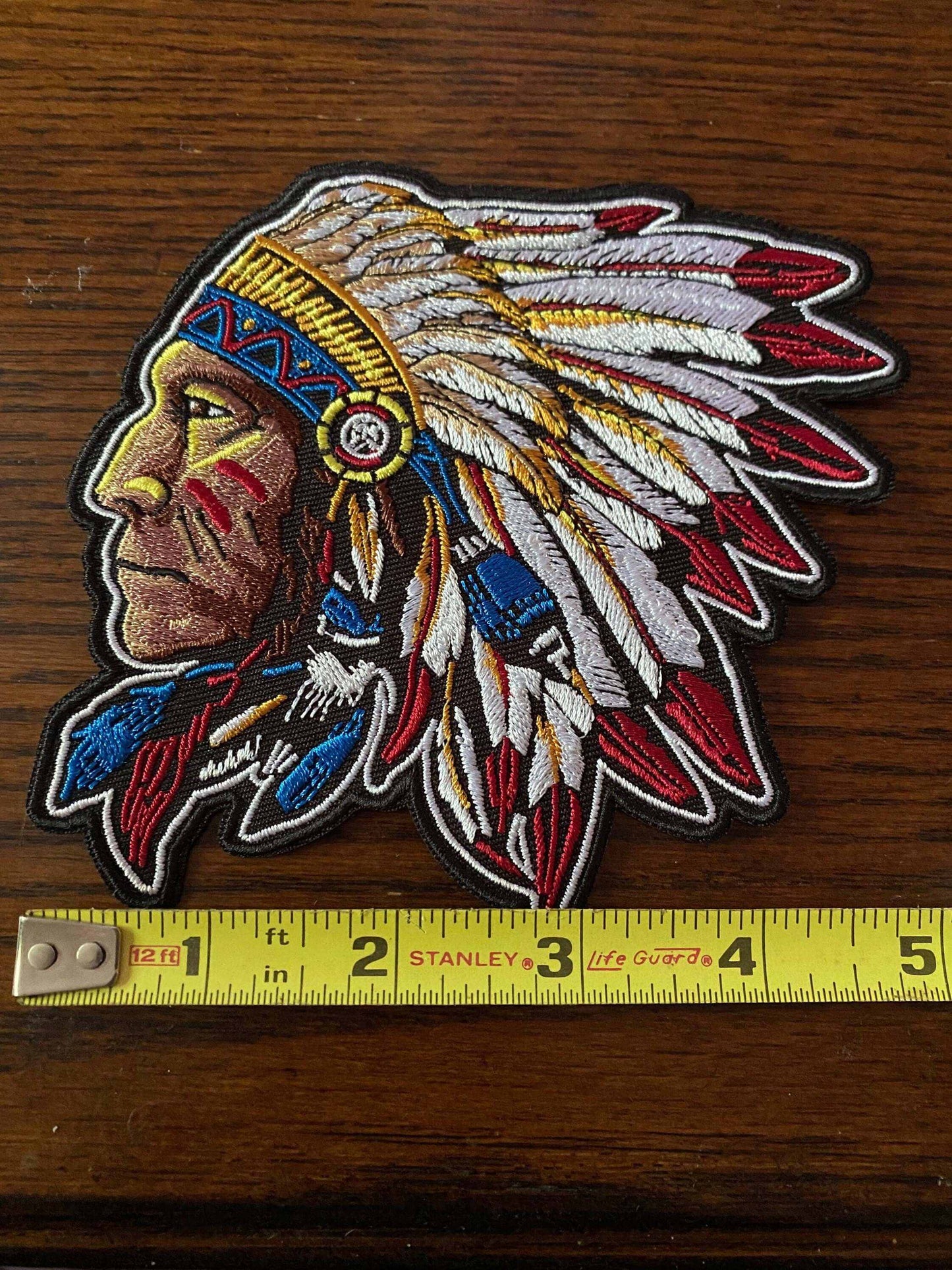 Chief patch embroidered with Native American chief profile wearing a detailed feather headdress, placed next to a measuring tape for size reference.