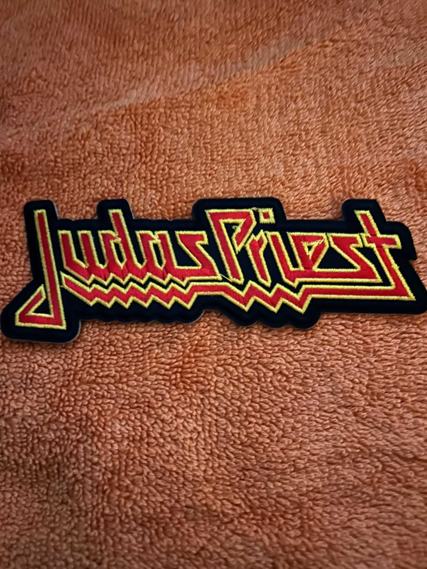 Hard Rock patch featuring Judas Priest logo in red and yellow embroidery on black background