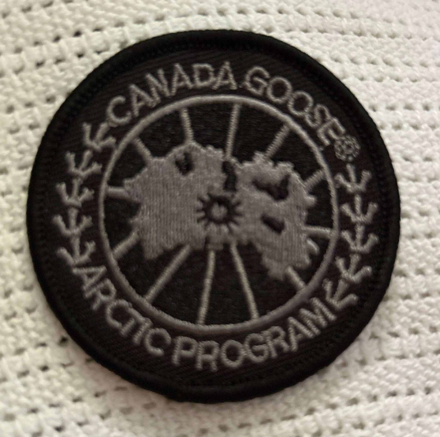 Black and gray Canada Goose Arctic Program circular patch on white fabric background