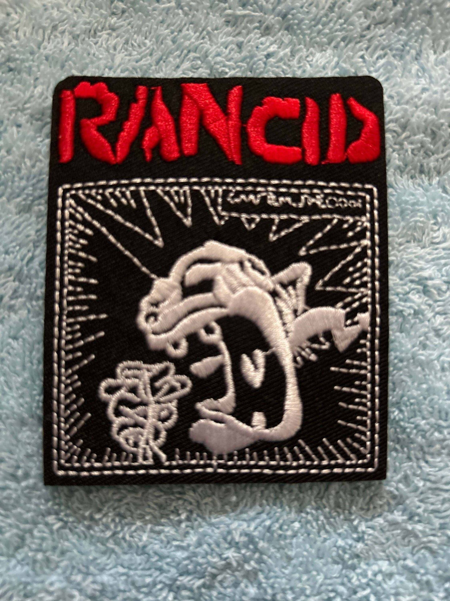 Rancid logo patch embroidered with red band name and black and white punk design on black background