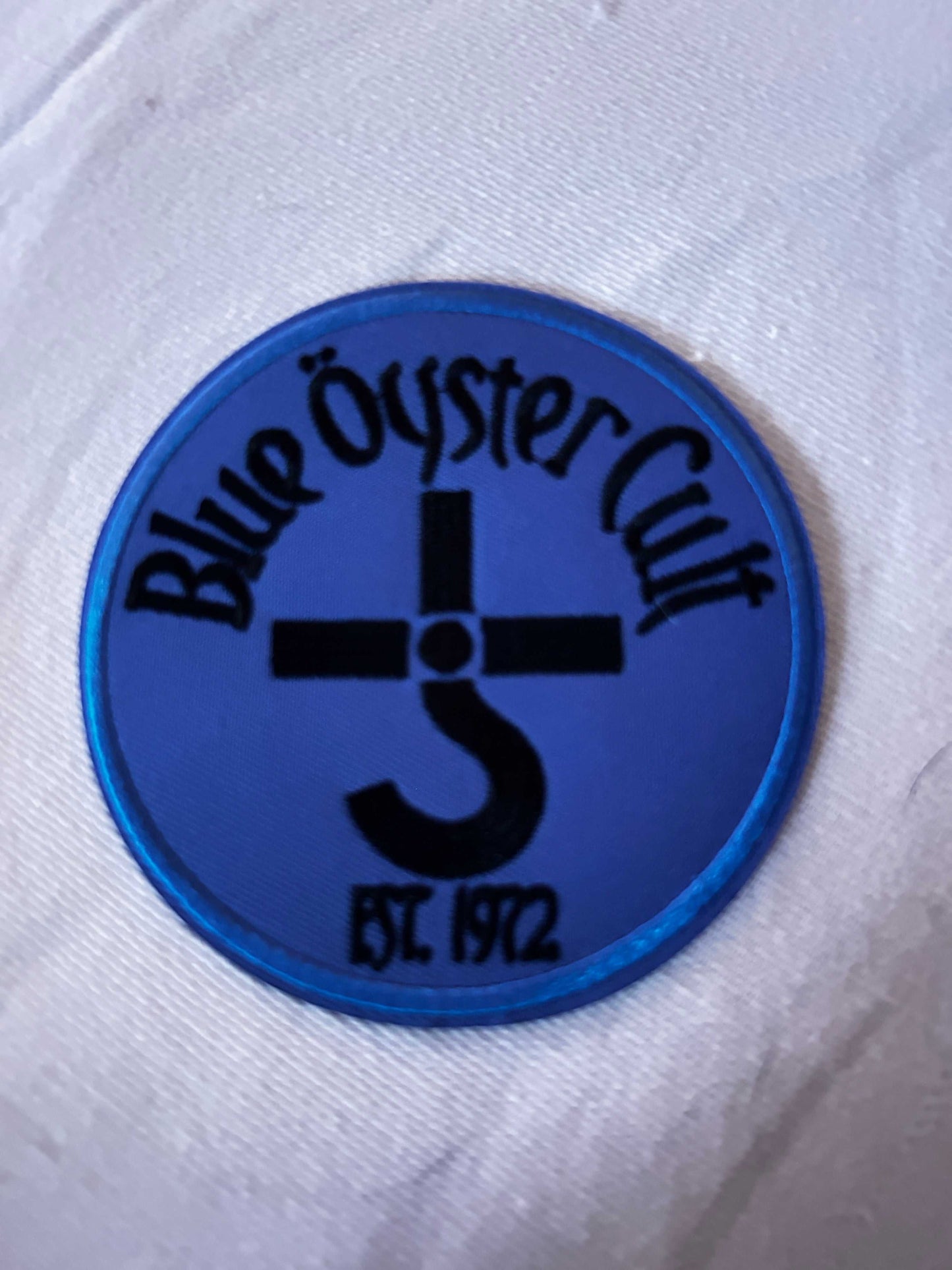 Blue Oyster Cult embroidered logo patch in blue with black text and symbol, 4-inch round design